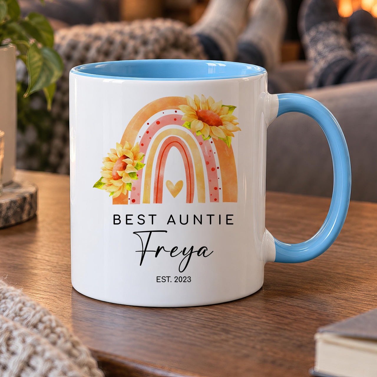 Personalised aunt mug: white mug with blue handle, a rainbow with sunflowers, BEST AUNTIE, the name Freya and EST. 2023