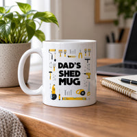 Dad's Shed mug in white on a wooden desk by a window