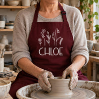 Burgundy apron with white wildflower print and 'CHLOE', worn at a pottery wheel - personalised apron