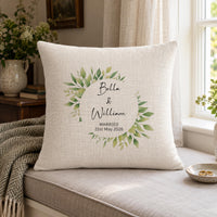 Cream cushion on a window seat with wedding rings nearby, leaf wreath and 'Bella & William Married' - personalised cushion