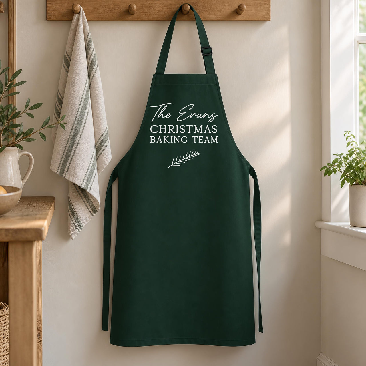 Bottle green 'The Evans CHRISTMAS BAKING TEAM' apron hanging on a wooden peg rail - personalised apron