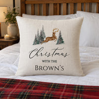 Linen-look cushion on a bed with a leaping reindeer, pine trees and 