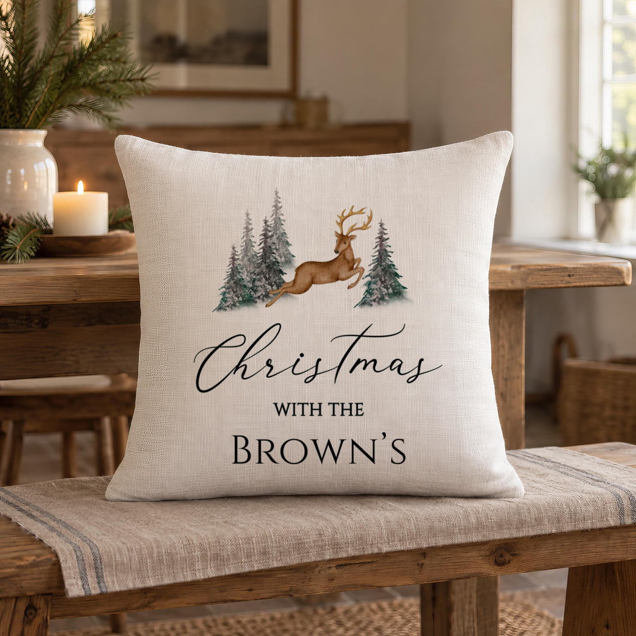 Linen-look cushion on a wooden bench with a watercolour reindeer and family surname in black text - personalised cushion