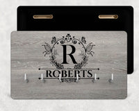 Grey wood-effect board, butterfly wreath 'R' monogram, 'ROBERTS' and six hooks, black back shown - personalised key holder