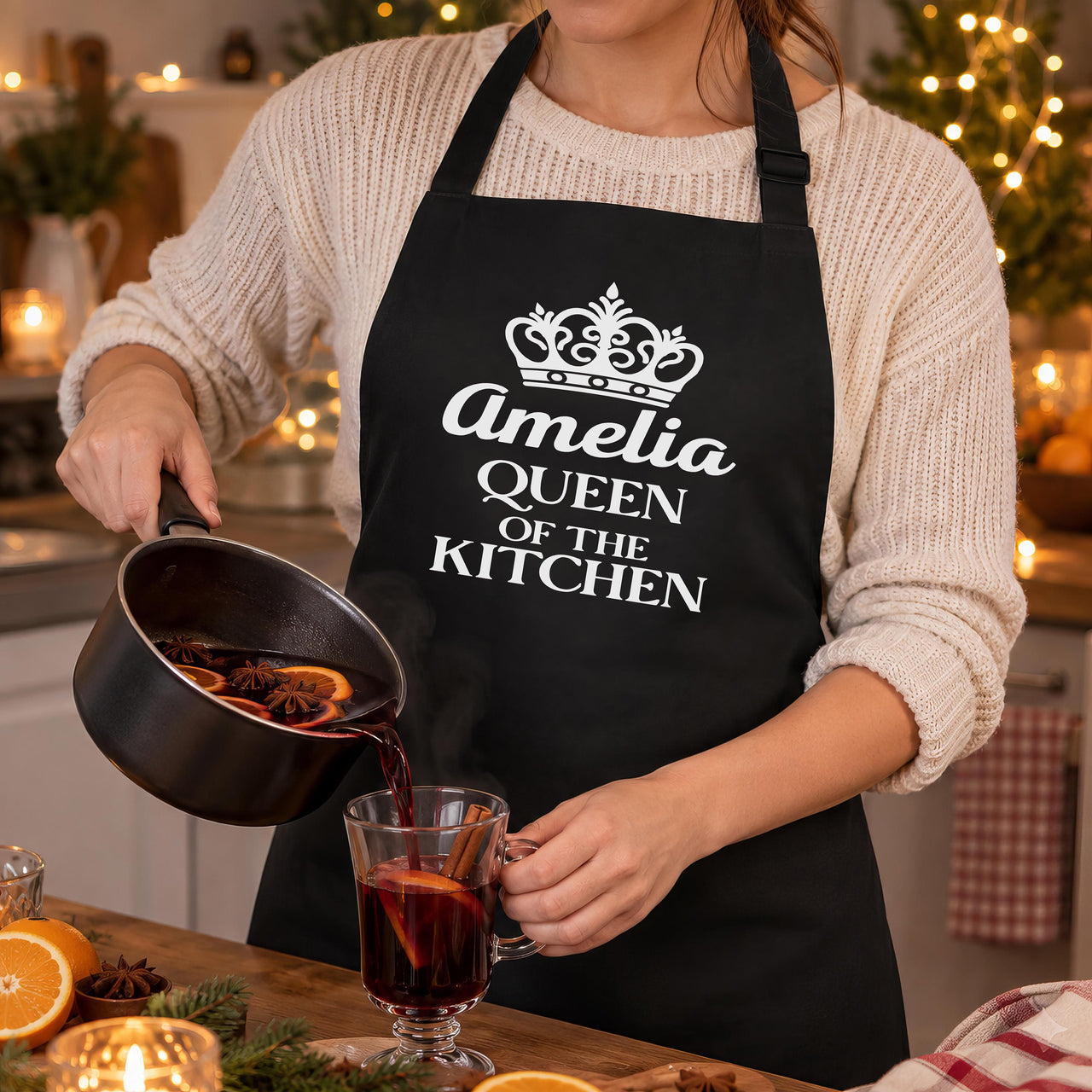 Black apron with white crown and 'Amelia QUEEN OF THE KITCHEN', pouring mulled wine - personalised apron