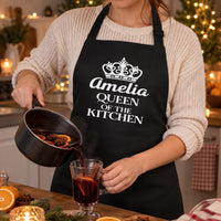 Black apron with white crown and 'Amelia QUEEN OF THE KITCHEN', pouring mulled wine - personalised apron