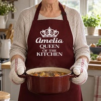 Burgundy apron with crown and 'Amelia QUEEN OF THE KITCHEN', holding a pot of stew - personalised apron