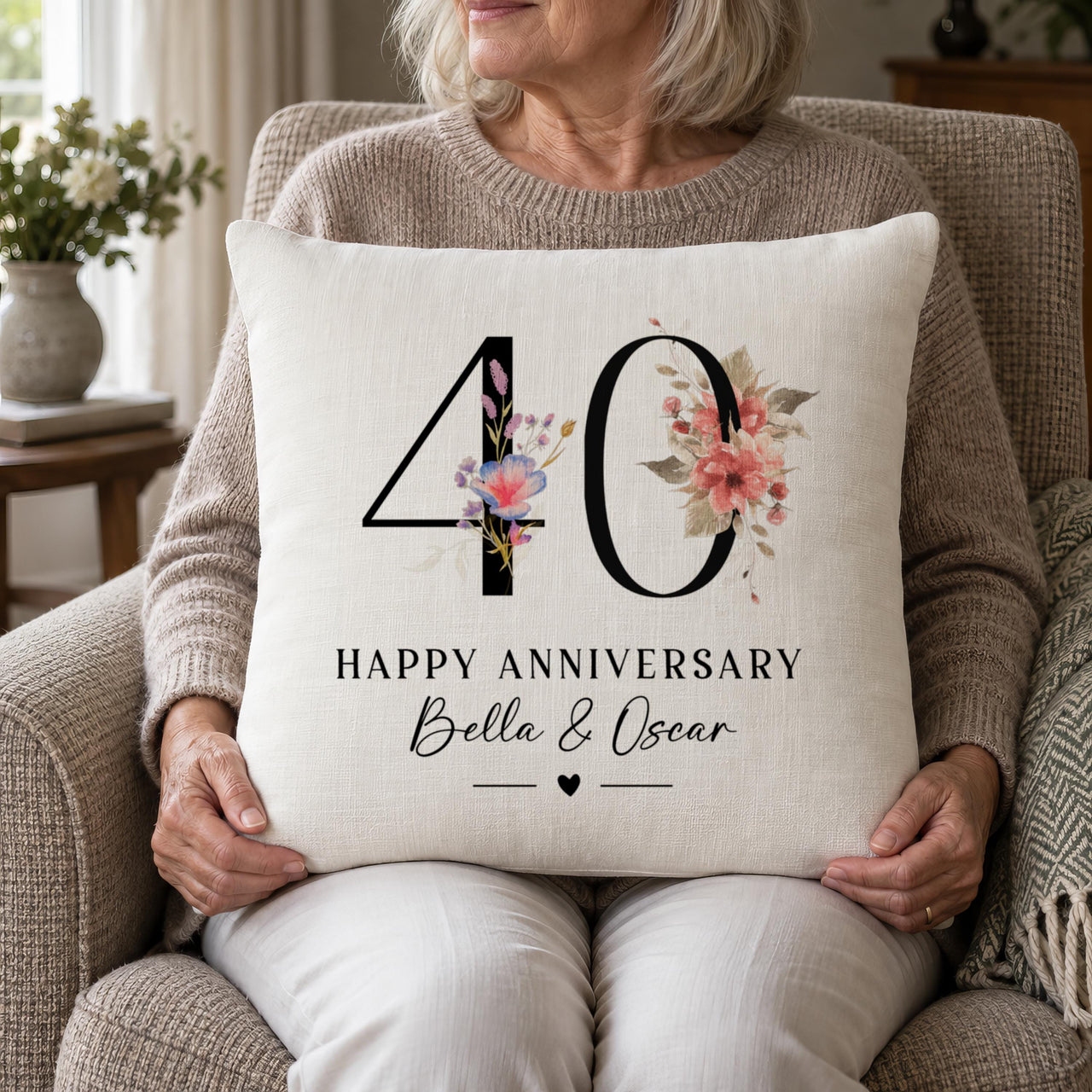 Woman holding a linen 40th "Happy Anniversary" cushion with pink flowers and "Bella & Oscar" - personalised cushion