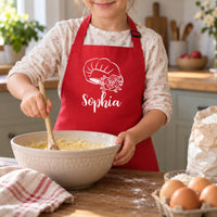 Child in a red apron with white chef hat, rose and 