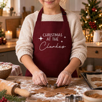 Child cutting gingerbread in a burgundy apron reading 