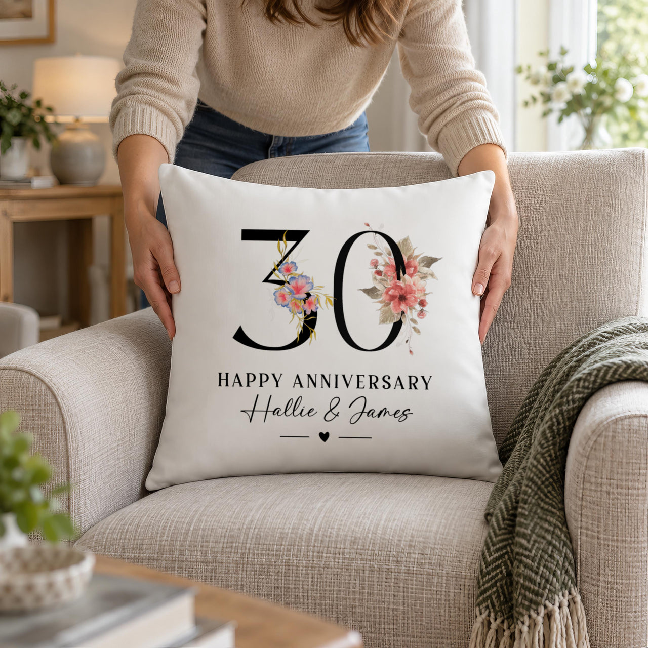 White cushion with floral '30', 'HAPPY ANNIVERSARY' and 'Hallie & James' placed on an armchair - personalised cushion