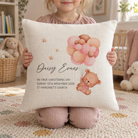 Girl holding a cream christening cushion with a bear on pink balloons, the name Daisy Evans, date and St Margaret's Church