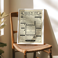 Vintage 1939 birthday newspaper print in a silver frame resting on a wooden chair in sunlight