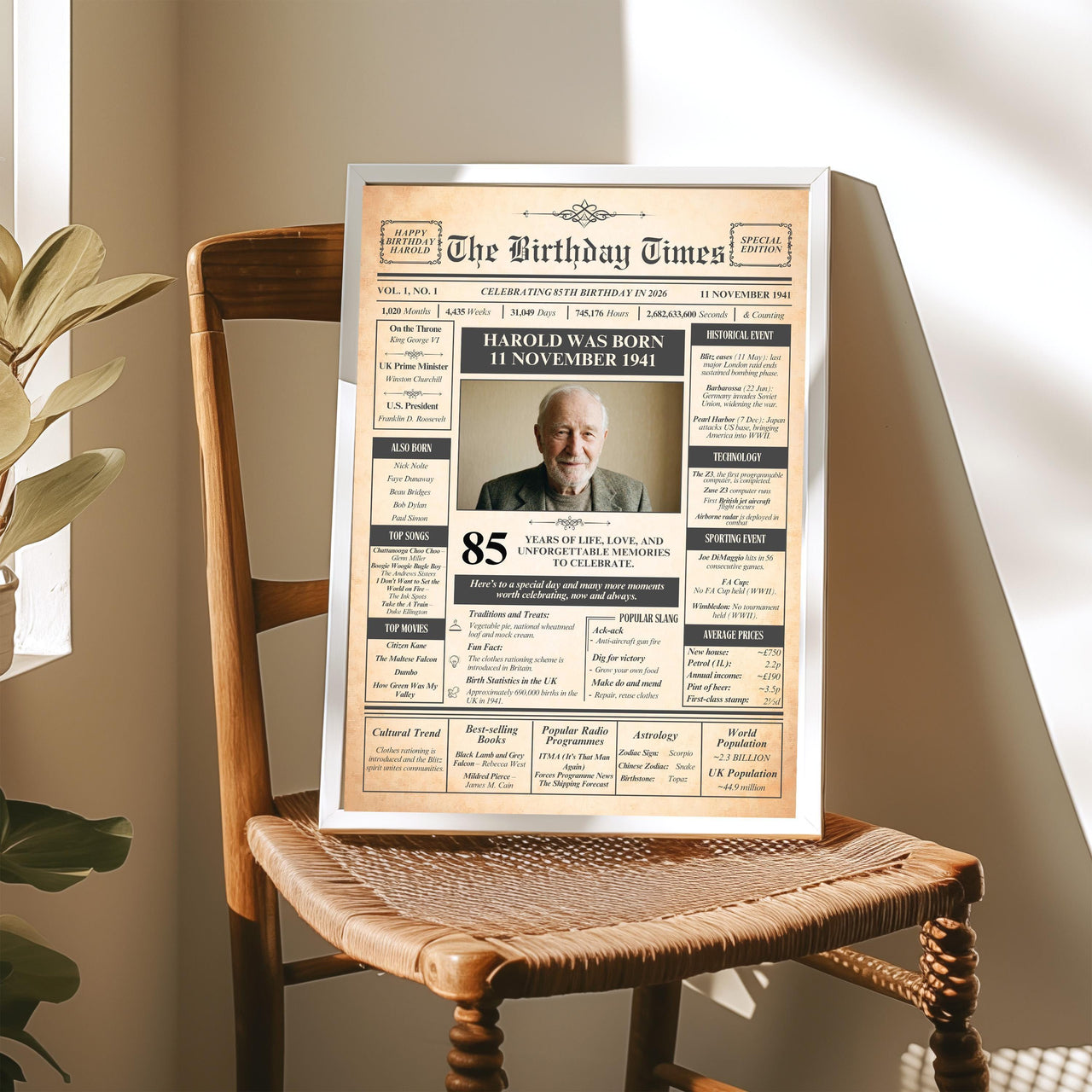 Silver framed newspaper style 85th birthday print propped on a wooden chair in a sunlit room