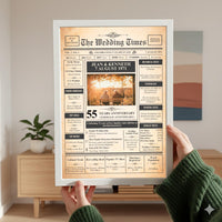 Person in a green jumper holding a white framed 55th anniversary newspaper poster in a living room