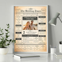Framed anniversary newspaper poster with couple photo on a white desk beside a plant and a grey lamp