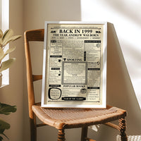 1999 birth year newspaper print in a silver frame resting on a wooden chair in warm sunlight