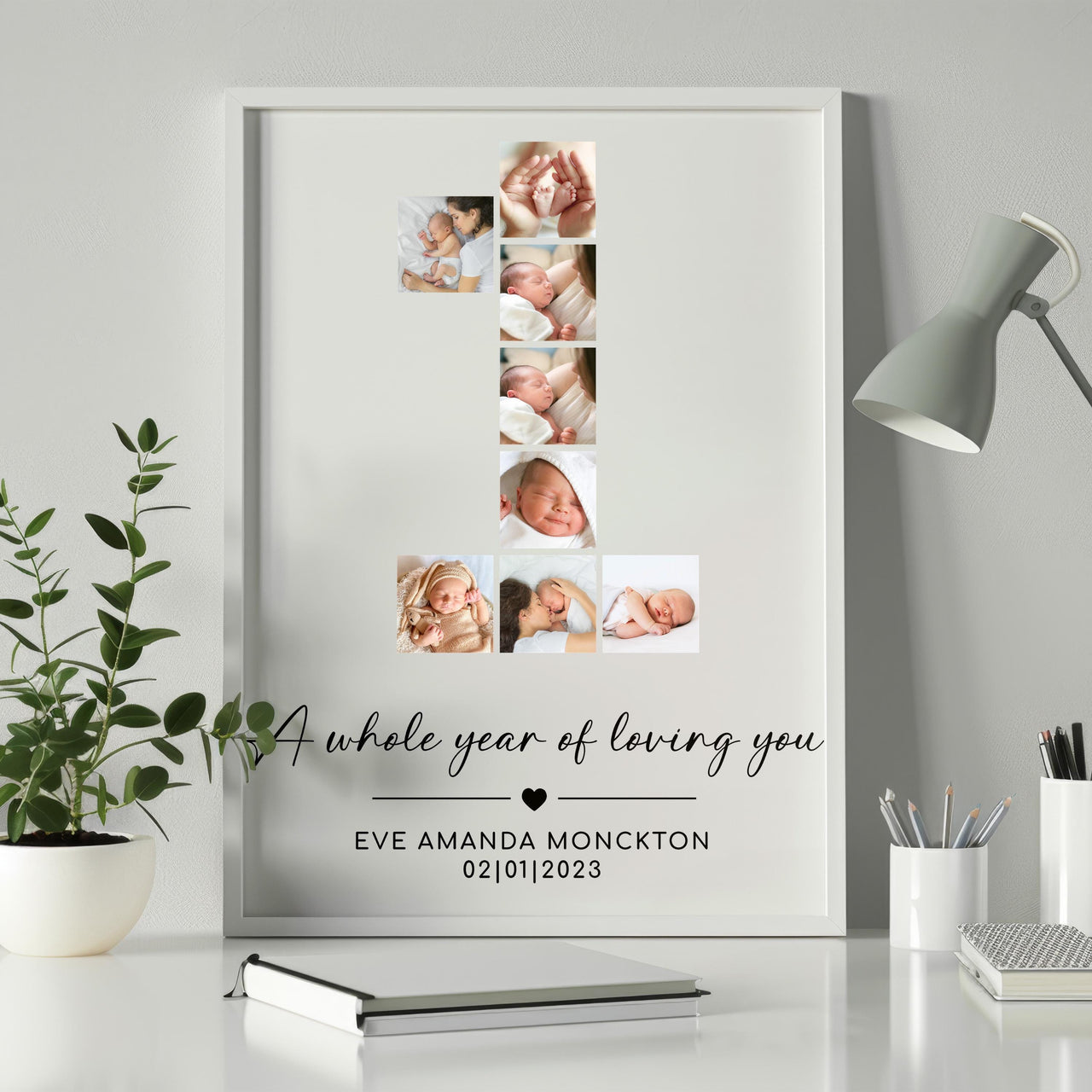 White framed first birthday photo collage shaped as the number 1 with a name and date, on a desk with a lamp