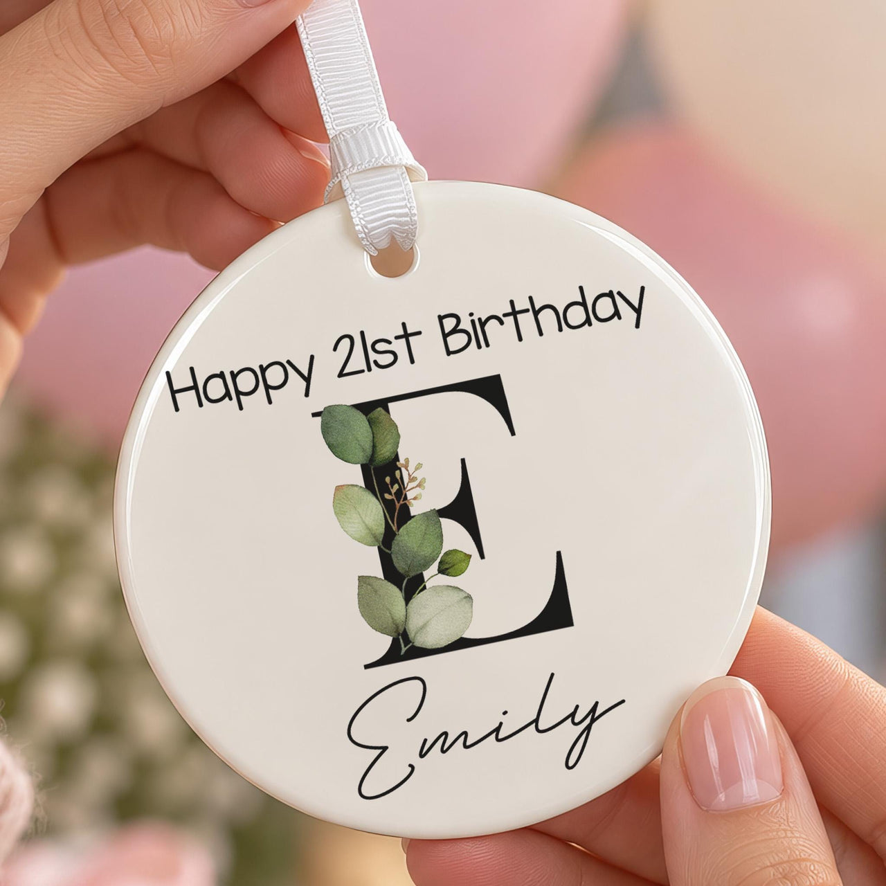 Leafy monogram ceramic ornament held in hands: black letter E with green leaves, Happy 21st Birthday and Emily in script