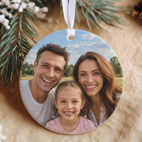Round white ceramic bauble printed edge to edge with a smiling family photo, hanging from a white ribbon