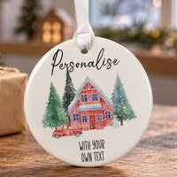 Round white ceramic bauble with a red cottage, snowy fir trees and a red truck, with sample text above and below