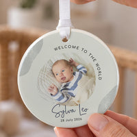 New baby ceramic ornament: sage green bauble with a round baby photo, Welcome to the World, Sylva Leo, 28 July 2026