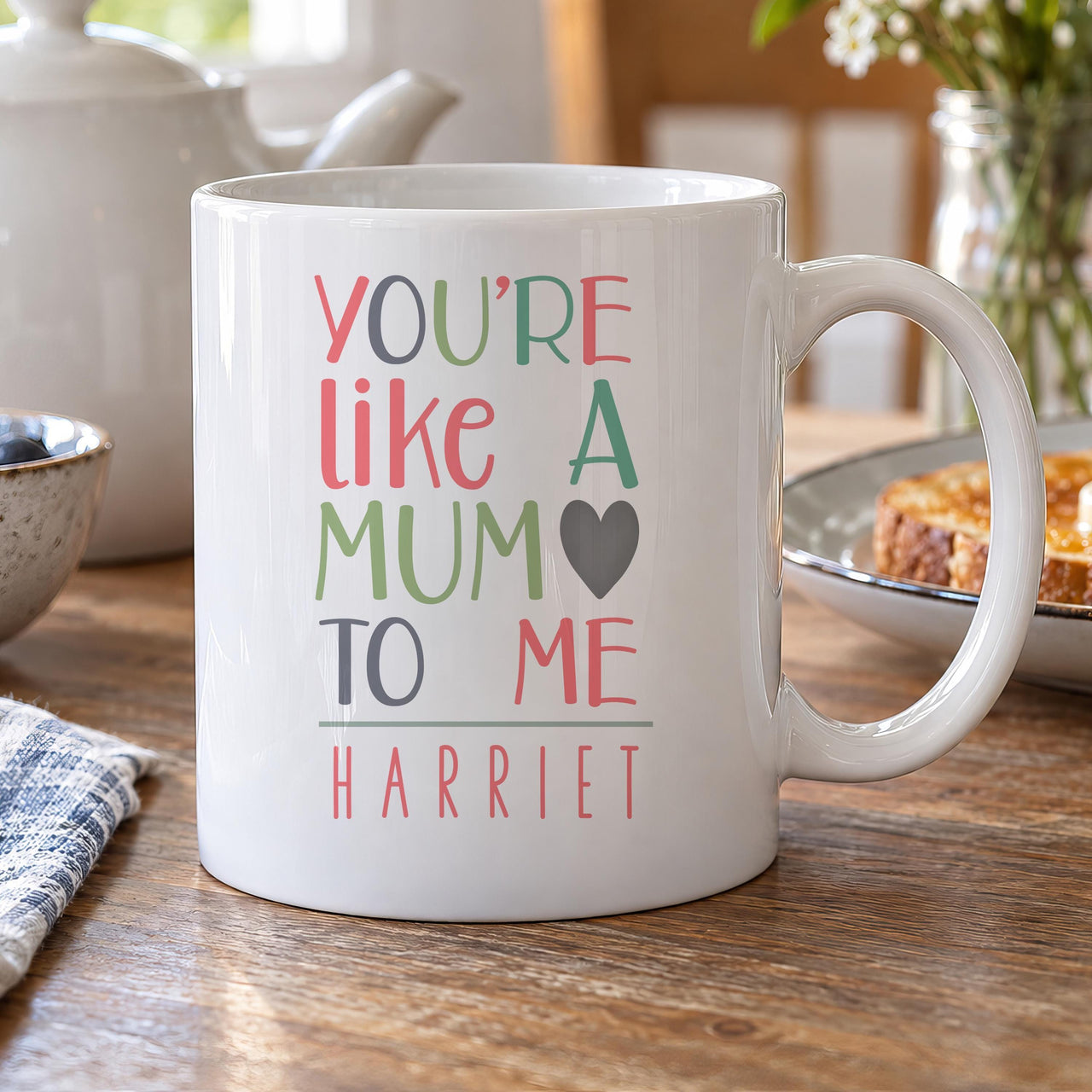 Personalised mum mug: white mug reading You're Like a Mum to Me in pink, green and grey with a heart and the name HARRIET