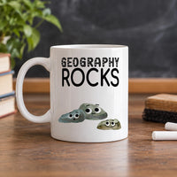 Geography Rocks mug in white on a wooden desk by a window