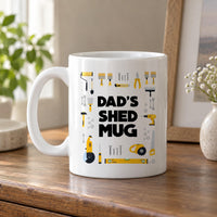 White 11oz Dad's Shed Mug on a wooden shelf next to flowers