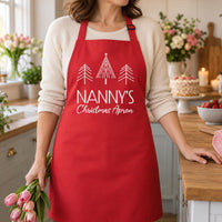 Red Nanny's Christmas Apron with white tree print, shown in a bright kitchen