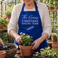 Royal blue apron reading 'The Evans CHRISTMAS BAKING TEAM', worn while potting plants - personalised apron