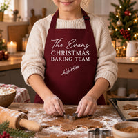 Child in burgundy apron reading 'The Evans CHRISTMAS BAKING TEAM' cutting gingerbread - personalised apron