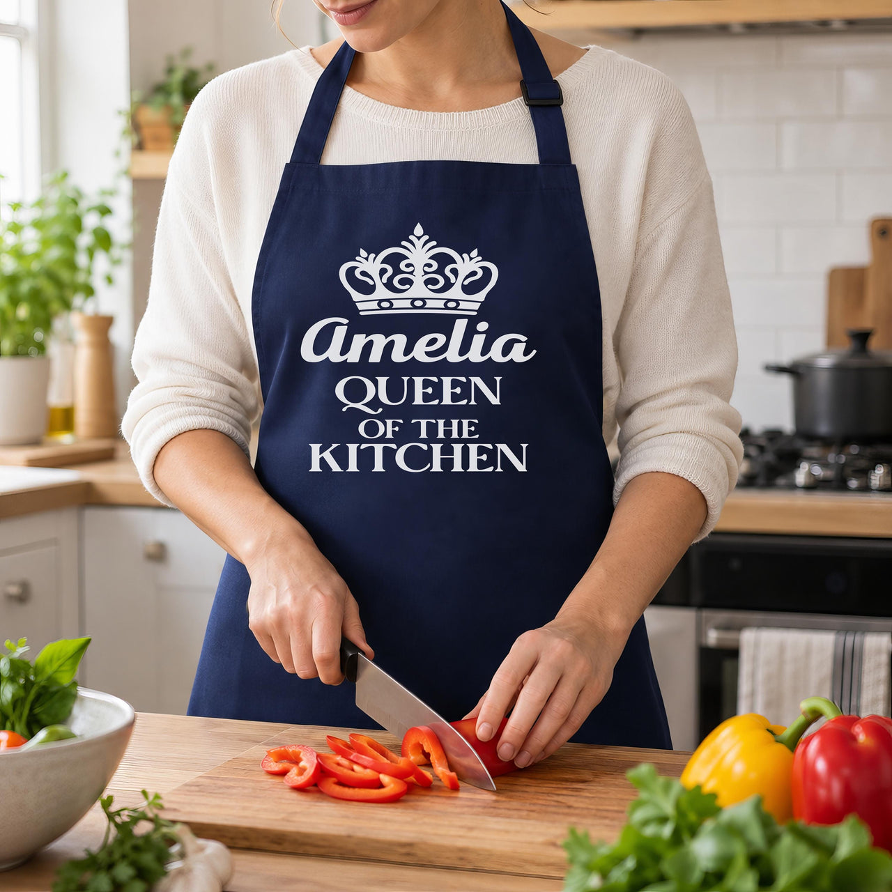 Navy apron with crown and 'Amelia QUEEN OF THE KITCHEN', slicing red peppers - personalised apron