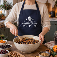 Navy apron with white cupcake and 'Amelia Cupcake Queen', stirring a bowl of dried fruit - personalised apron