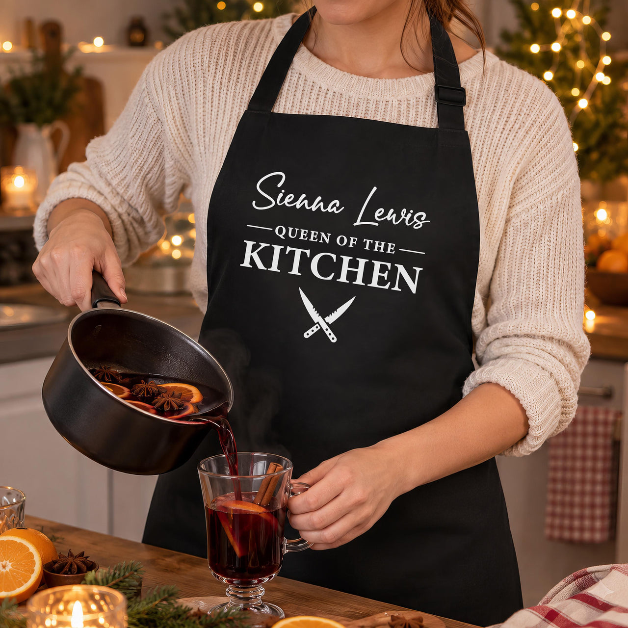 Black Queen of the Kitchen apron with a name, worn while pouring mulled wine