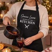 Black Queen of the Kitchen apron with a name, worn while pouring mulled wine