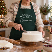 Woman icing a cake in a bottle green apron with white 