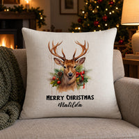 Linen-look reindeer wreath cushion 'MERRY CHRISTMAS Matilda' by a lit Christmas tree and fire - personalised cushion