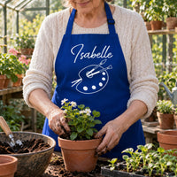 Royal blue apron with 'Isabelle' and paint palette, worn while potting plants - personalised apron