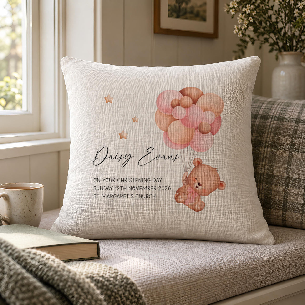 Personalised christening bear cushion on a window seat next to a mug and a book