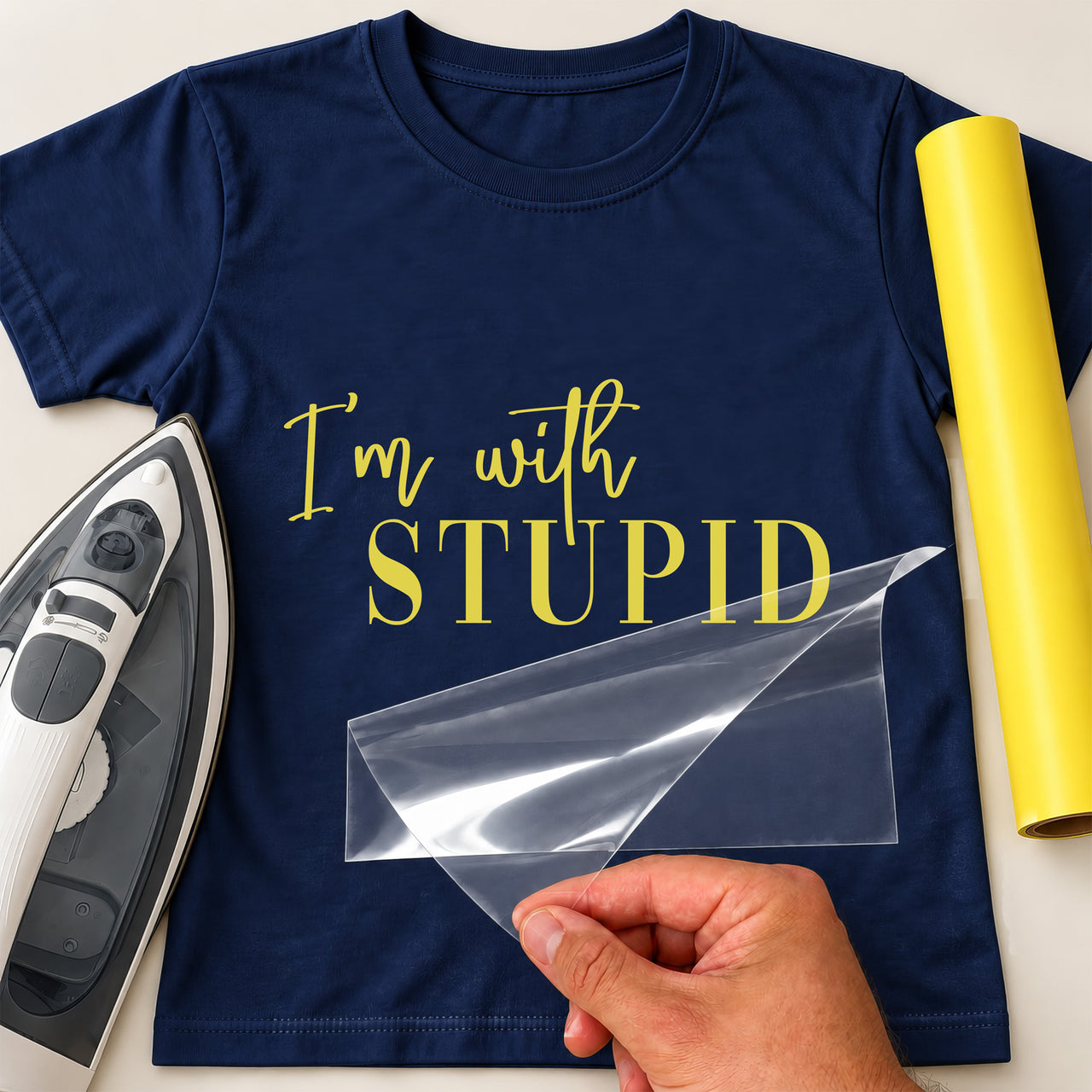 Navy T-shirt with yellow "I'm with stupid" lettering in script and serif capitals, iron and yellow vinyl roll beside it