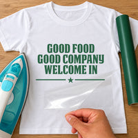 Menu or rules iron-on text: green GOOD FOOD GOOD COMPANY WELCOME IN on a white T-shirt, film being peeled