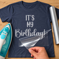 It's My Birthday Flamingo iron-on transfer: silver IT'S MY Birthday! on a navy T-shirt, film being peeled