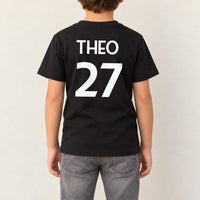 Kids Sports Kit Name Number Iron-On Transfer, shown on a black kids t-shirt (back view)