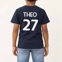 Kids Sports Kit Name Number Iron-On Transfer, shown on a navy kids t-shirt (back view)