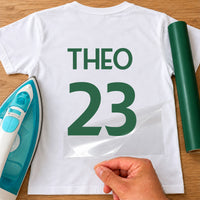 Kids Sports Kit Name Number iron-on transfer: green THEO 23 on a white T-shirt, film being peeled