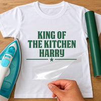 King of the Kitchen name iron-on transfer: green KING OF THE KITCHEN HARRY with a star on a white T-shirt, film being peeled