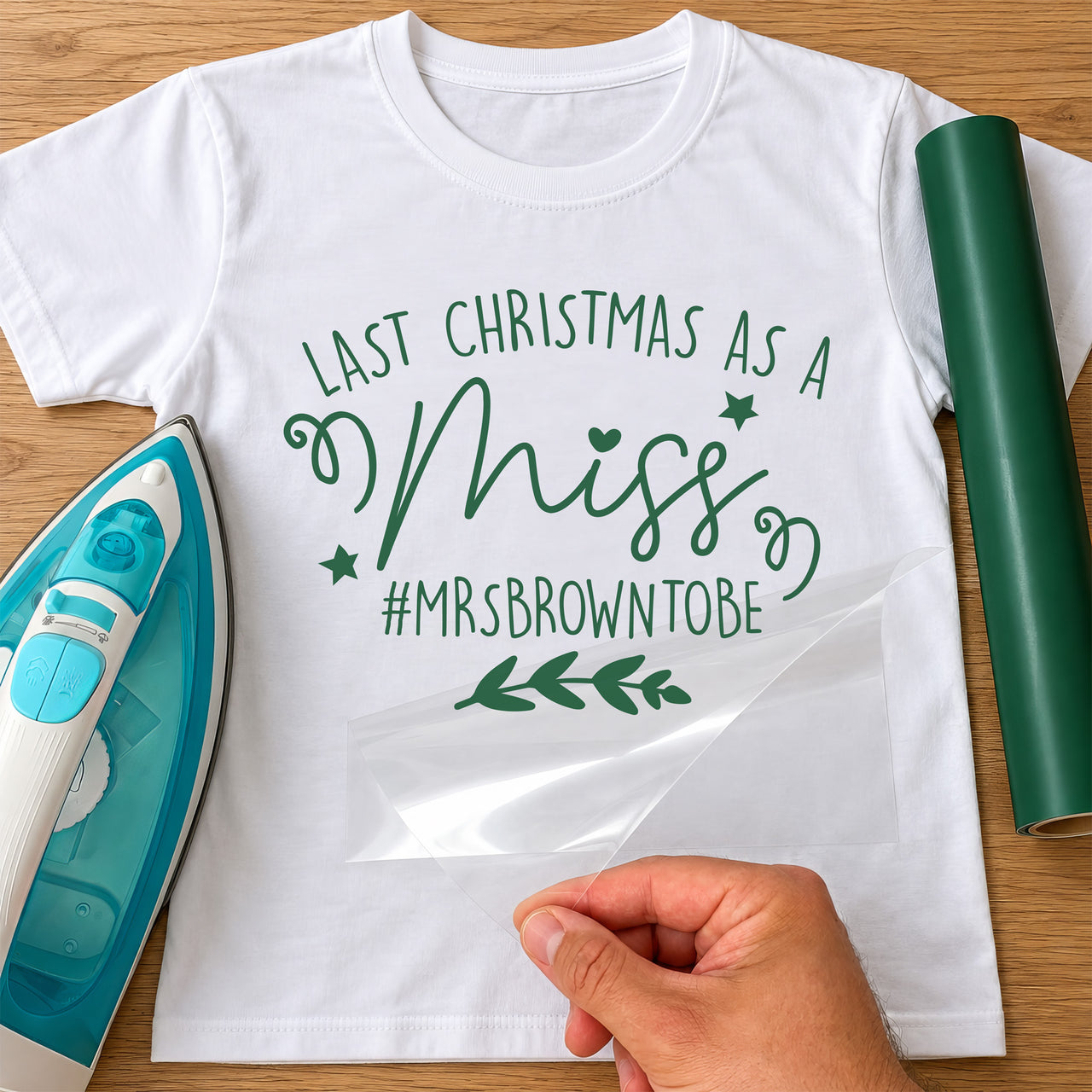 Mockup: white T-shirt with green vinyl 'Last Christmas as a Miss' and '#MRSBROWNTOBE', stars, swirls and a sprig