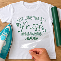 Mockup: white T-shirt with green vinyl 'Last Christmas as a Miss' and '#MRSBROWNTOBE', stars, swirls and a sprig