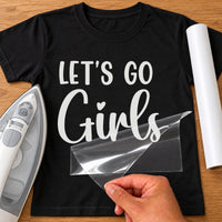 Black T-shirt with white 'LET'S GO Girls' and a heart above the i, hen party iron-on transfer beside a white roll